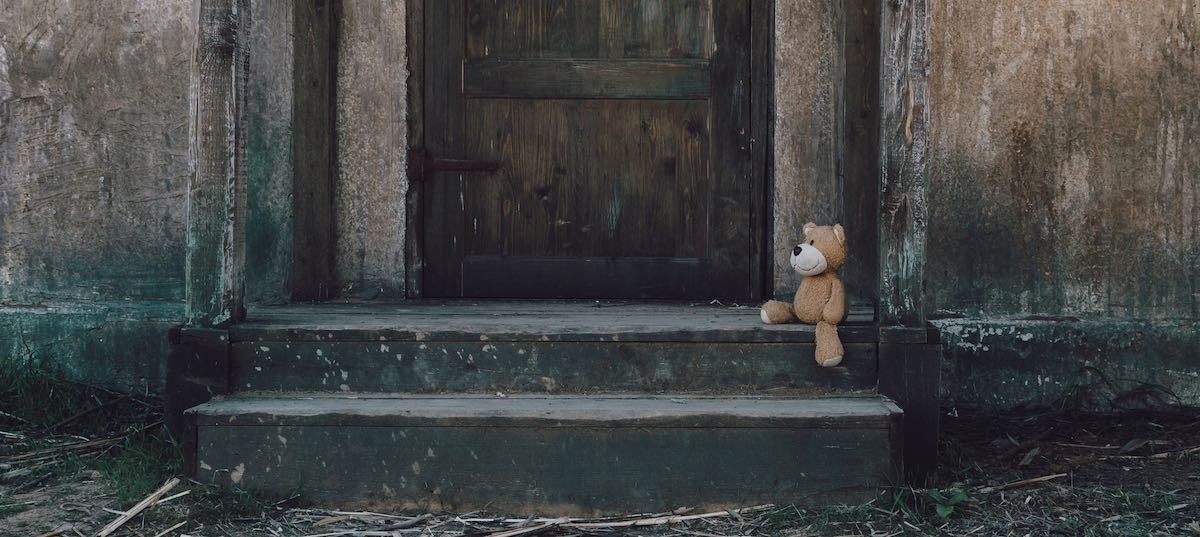Teddy sitting on a rustic doorstep